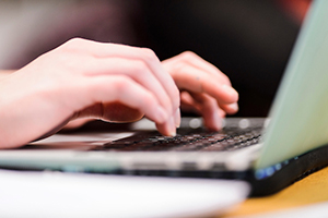 Hands typing on a laptop computer