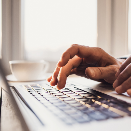 A person's hand hovering over a laptop keyboard.